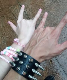 two hands with spikes on their wrist and bracelets attached to each other's wrists