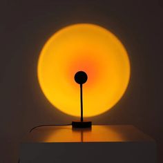 a lamp that is sitting on top of a white surface with a yellow light behind it