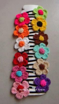 crocheted flower hair combs are lined up on a striped tablecloth with black and white stripes