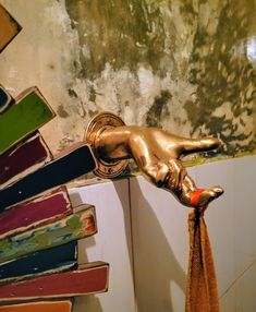 a gold faucet on the side of a bathtub with books in it