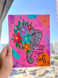 a person holding up a piece of art with an elephant and flowers painted on it