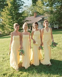 four bridesmaids in yellow dresses posing for a photo outside on the grass with their bouquets