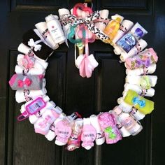 a wreath made out of baby items is hanging on the front door's black door