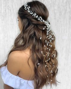 the back of a woman's head with long hair and pearls in her hair