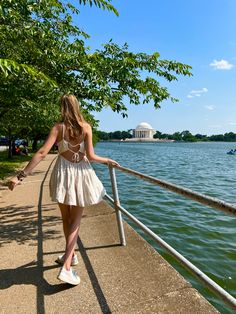 a woman is walking along the railing by the water