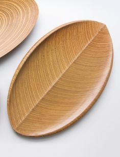 two wooden plates sitting next to each other on a white surface with an oval design