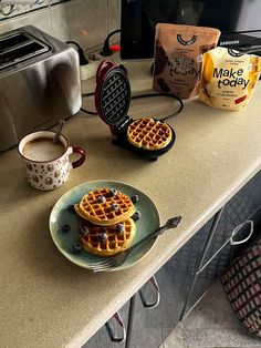 two waffles on a plate with blueberries and coffee in front of them