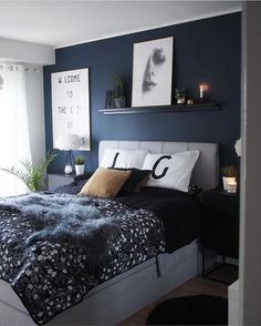 a bedroom with dark blue walls and white bedding, black comforter and pillows