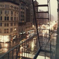 a city street filled with lots of traffic next to tall buildings in the rain at night