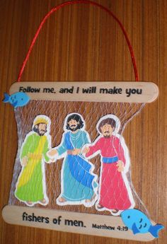 an ornament hanging on a wooden table with jesus and two other people holding hands