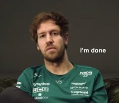 a man sitting on top of a green couch next to a black wall with a quote above it