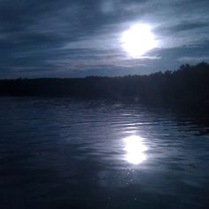 the sun shines brightly through the clouds over the water in front of some trees