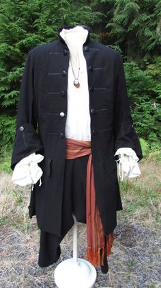 a man's black coat and white shirt is on display in front of some trees