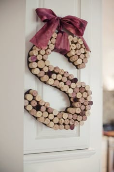 a door hanger made out of wine corks with a bow on it's head