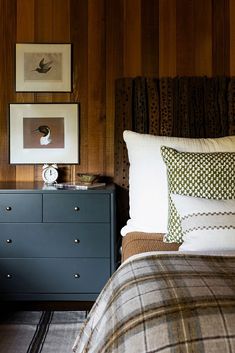 a bed room with a neatly made bed next to a dresser and pictures on the wall