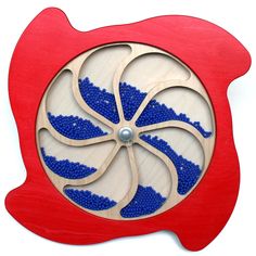 a red clock with blue beads on it's face and an eyeball in the center