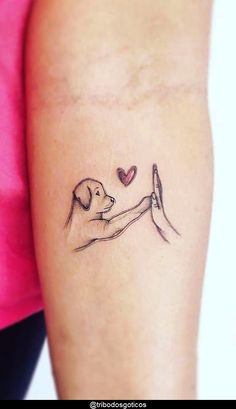 a woman with a small tattoo on her arm holding a dog's paw in the shape of a heart