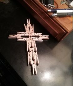 a wooden cross sitting on top of a table next to a pen and pencil holder