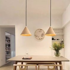 a dining room table with three lights hanging from it's ceiling and two benches in front of the table