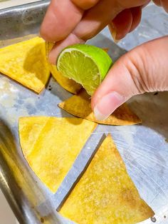 someone is peeling an avocado into some tortilla chips on a tray