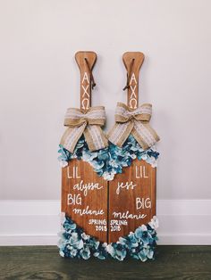 two wooden signs with blue flowers on them are attached to the side of a wall