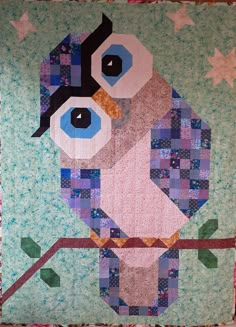 a quilted owl sitting on top of a tree branch with stars in the background