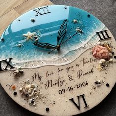 a clock that is on the ground with sand and seashells in front of it