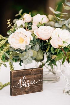 a vase filled with flowers sitting on top of a table next to a wooden sign