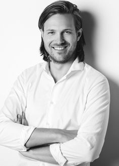 a black and white photo of a man with his arms crossed smiling at the camera