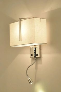 Wall-mounted lamp with a rectangular fabric shade emits warm light. Beneath, a flexible metal reading light protrudes, adding to the modern decor.