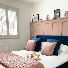 a dog laying on top of a bed in a room with pink and blue pillows