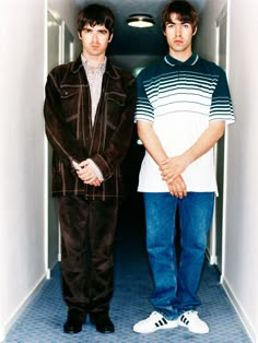 two young men standing next to each other in an open doorway with their hands on their hips