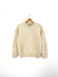 a white sweater hanging on a wooden hanger