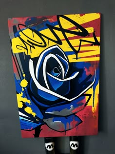 a painting with blue and yellow flowers on it is hanging up against a gray wall