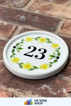 a white plate with yellow flowers and the number 23 painted on it's side