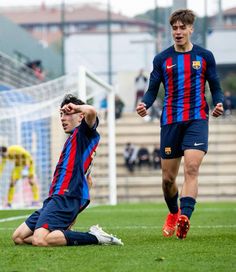 two soccer players are on the field during a game, one has his head in his hands