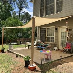 a patio with a table and chairs under an awning in the back yard area