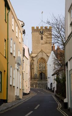 a narrow street with buildings and a clock tower in the backgroung area