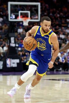 a basketball player dribbling the ball during a game with other players in the background