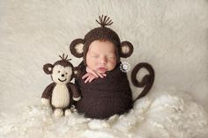 a baby sleeping next to a stuffed monkey on top of a white fur covered blanket