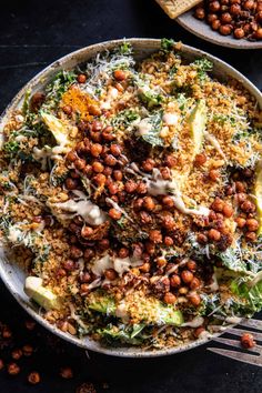 a bowl filled with lots of food next to a fork and some crackers on the side