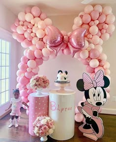 a minnie mouse balloon arch is decorated with balloons and other decorations for a birthday party