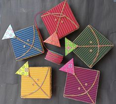 four different colored kites sitting on top of a black cloth covered table with string wrapped around them