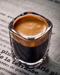 a cup of coffee sitting on top of an open newspaper