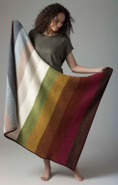 a woman is holding up a multicolored blanket