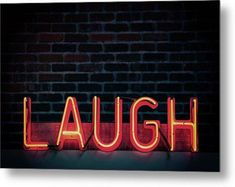 the word laugh spelled with neon lights in front of a brick wall and dark background