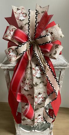 a large red and white bow on top of a metal container with ribbon around it