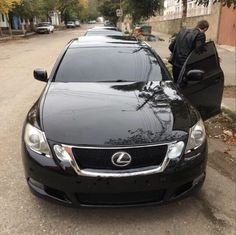 a black car parked on the side of a road next to a man with a suit case