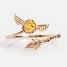 two gold rings with an orange and white diamond in the middle one has a bird on it's back