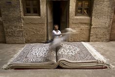 a man is standing in the doorway of an old building with two large rugs